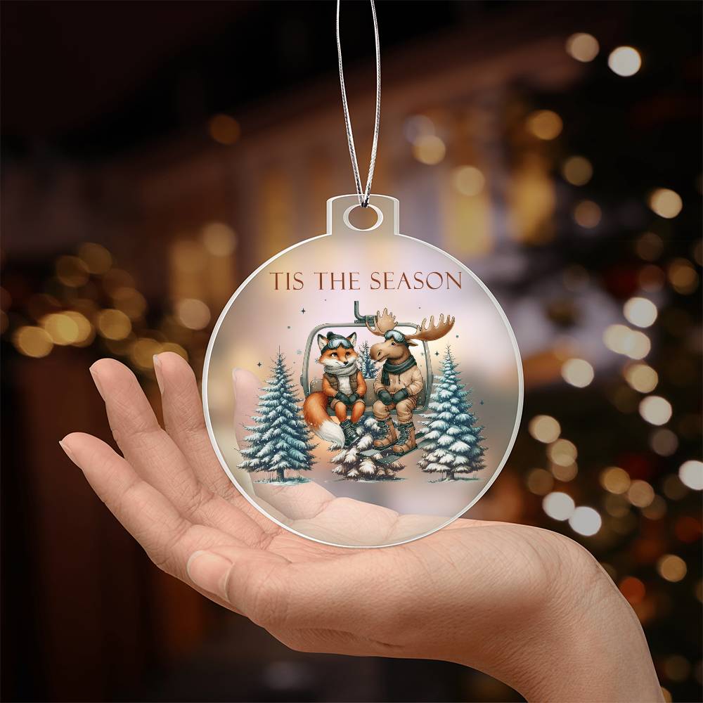 Acrylic Christmas ornament featuring a fox and moose on a ski lift with the words "Tis The Season."
