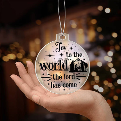 Clear Christmas ornament with nativity scene and "Joy to the World" text.
