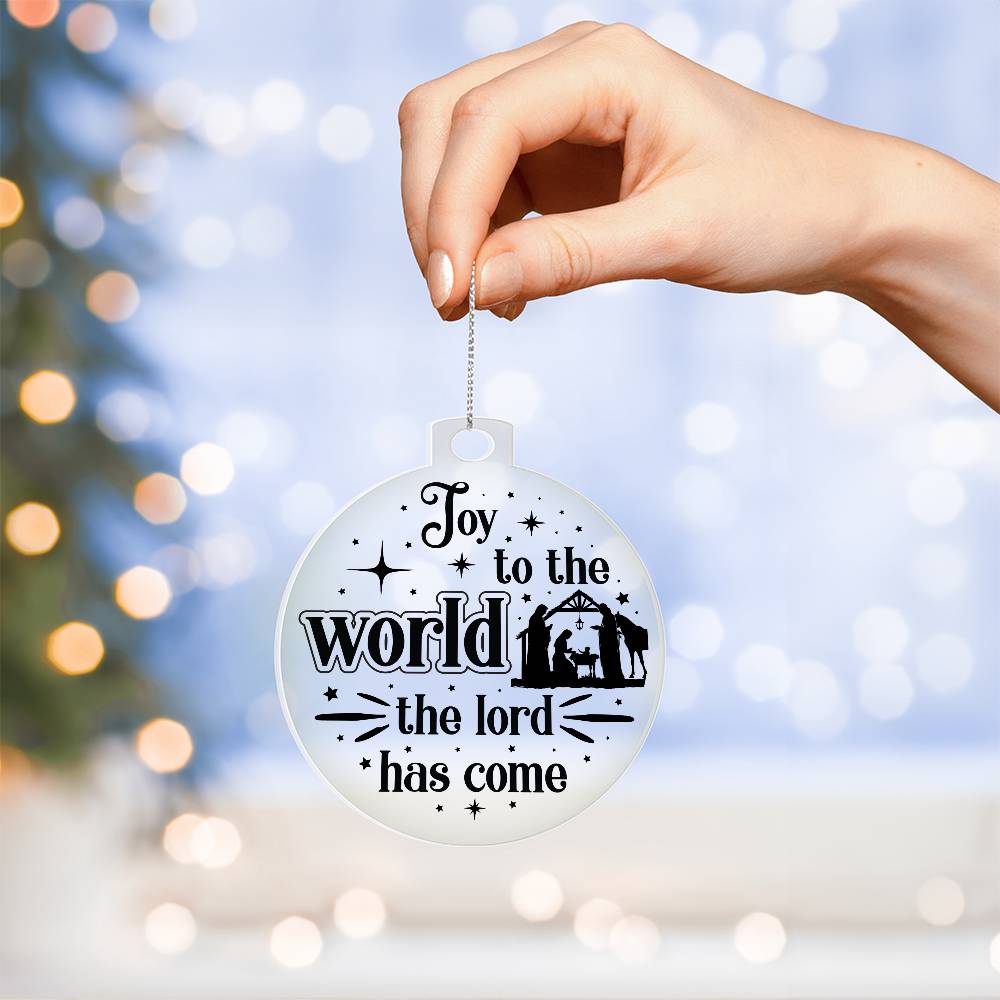 Clear Christmas ornament with nativity scene and "Joy to the World" text.
