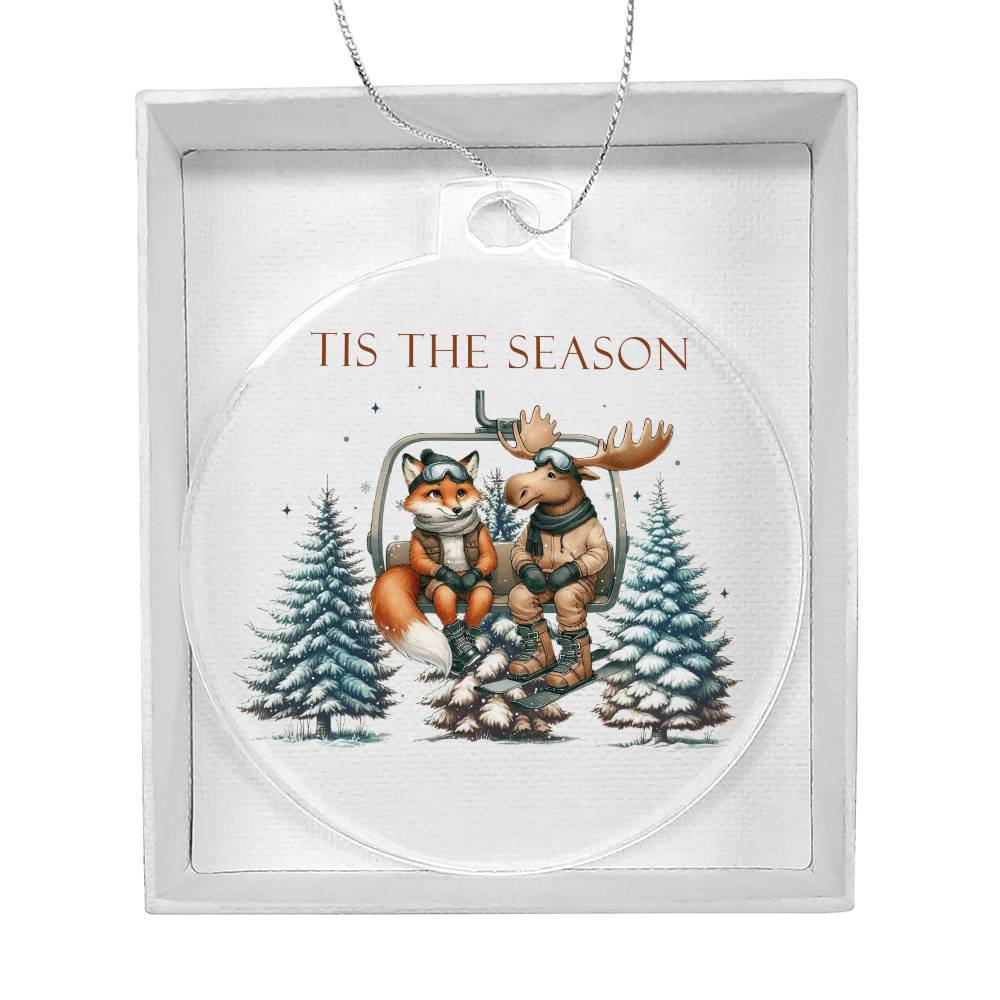 Acrylic Christmas ornament featuring a fox and moose on a ski lift with the words "Tis The Season."
