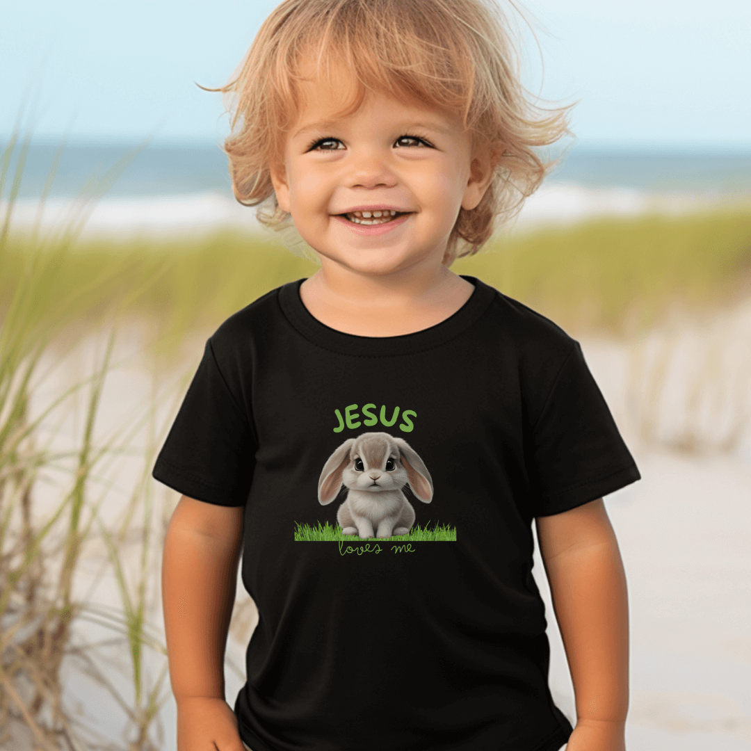 Jesus Loves Me toddler Christian tee with bunny on grass in vibrant colors.
